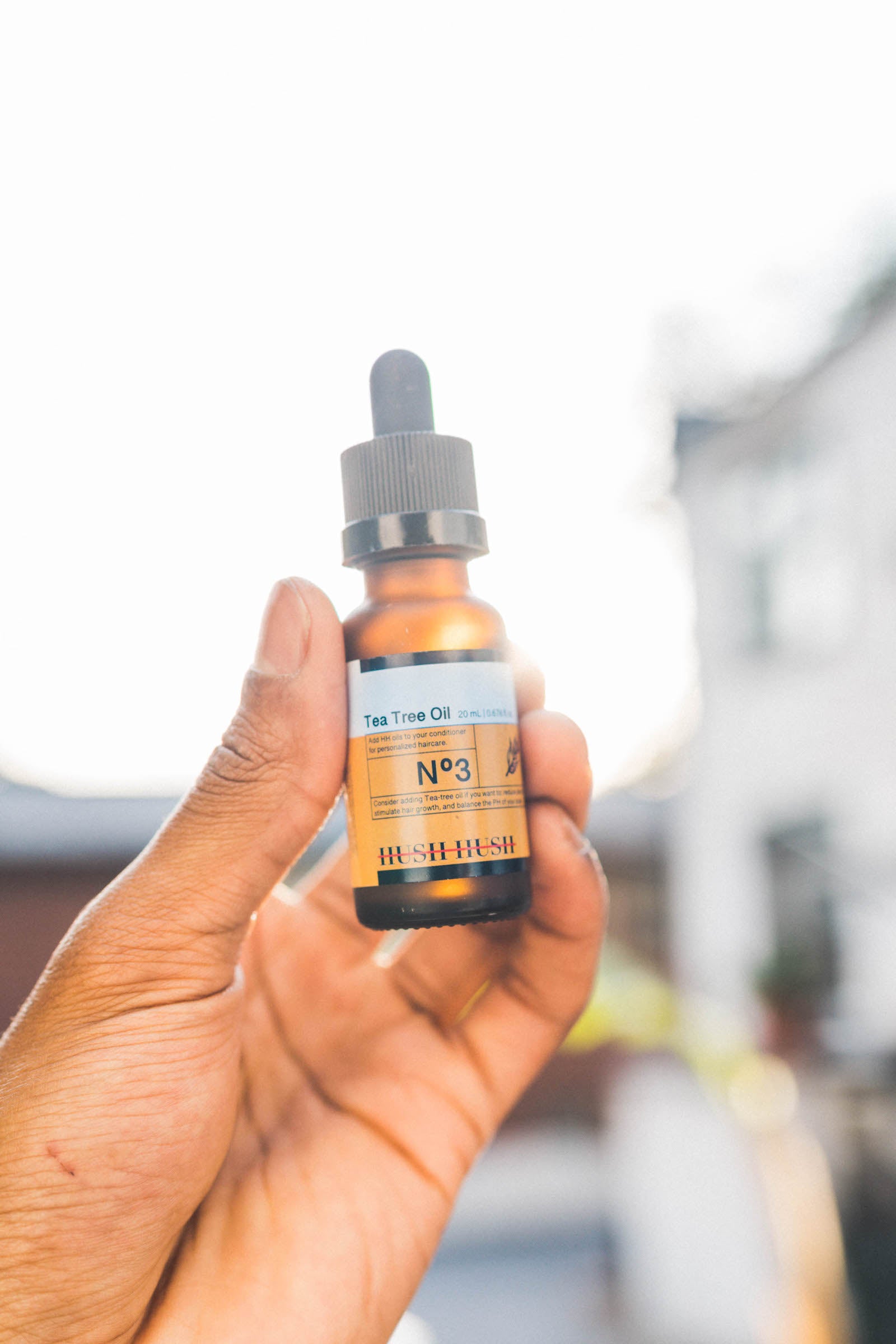 Tea tree oil being held up towards the sun. The perfect solution to encourage hair growth